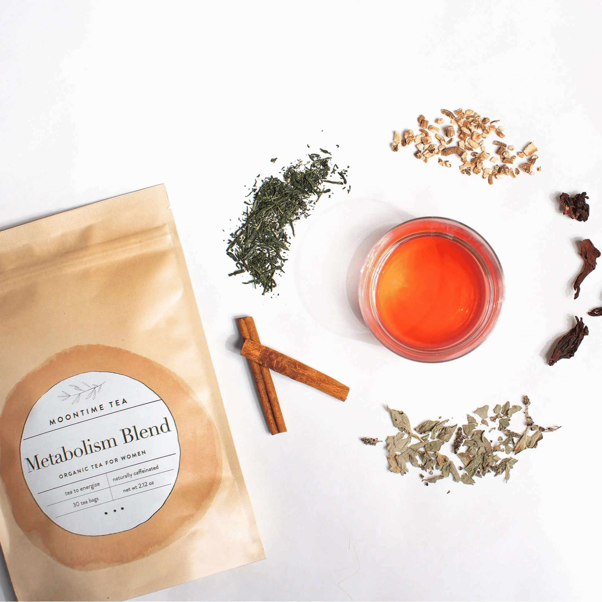 Alternate image of cup of tea surrounded by leaves and flowers from the tea and bag of tea